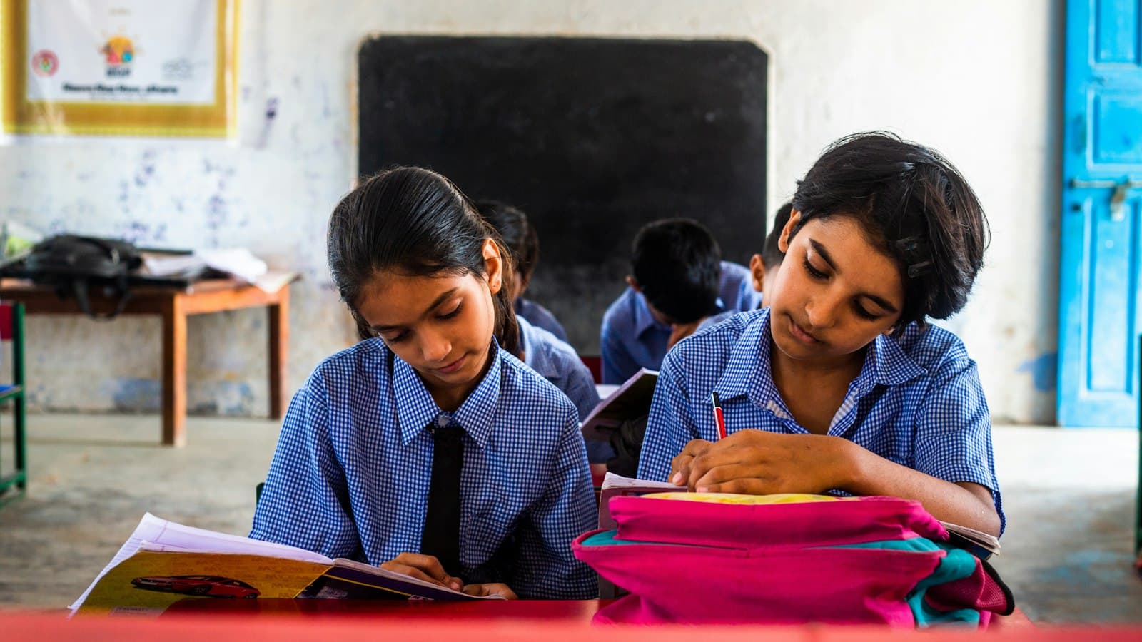 Two schoolgirls writing in their notebooks