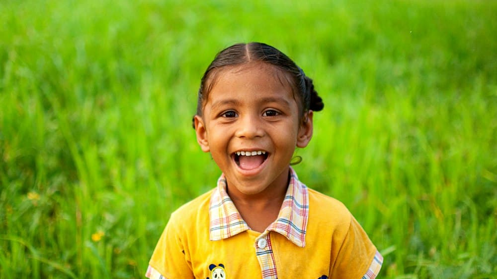 A young girl laughing in a green field