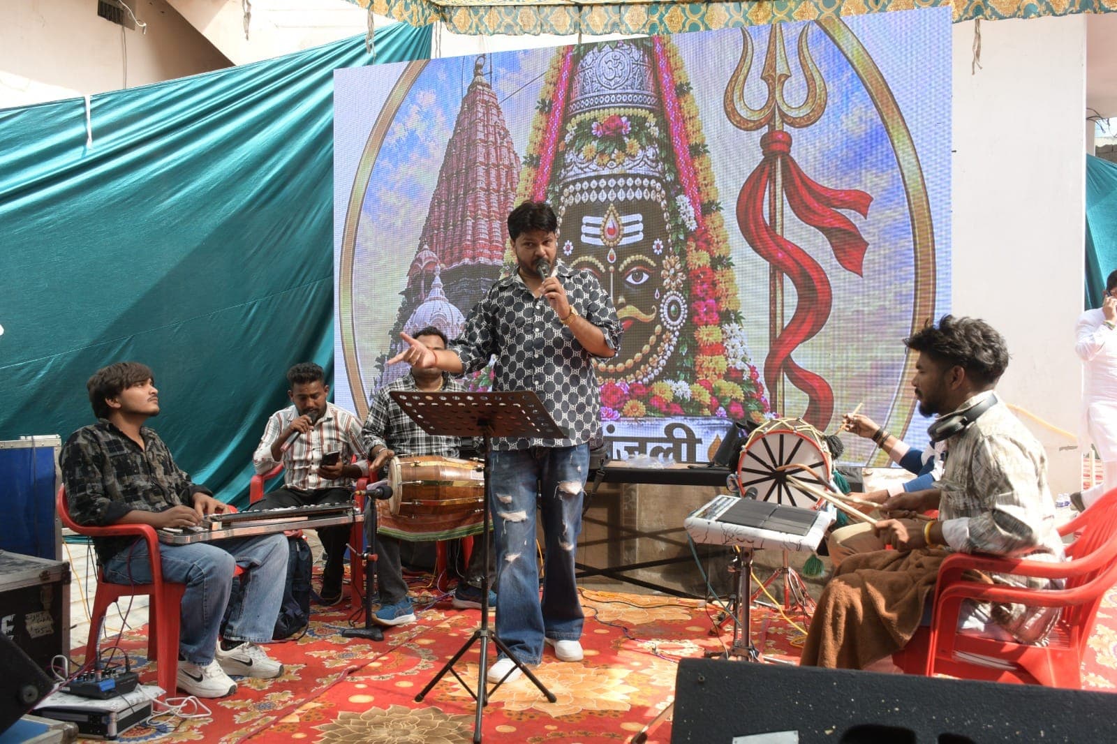 एलईडी स्क्रीन के सामने मंच पर गायक और संगतकार कार्यक्रम प्रस्तुत करते हुए