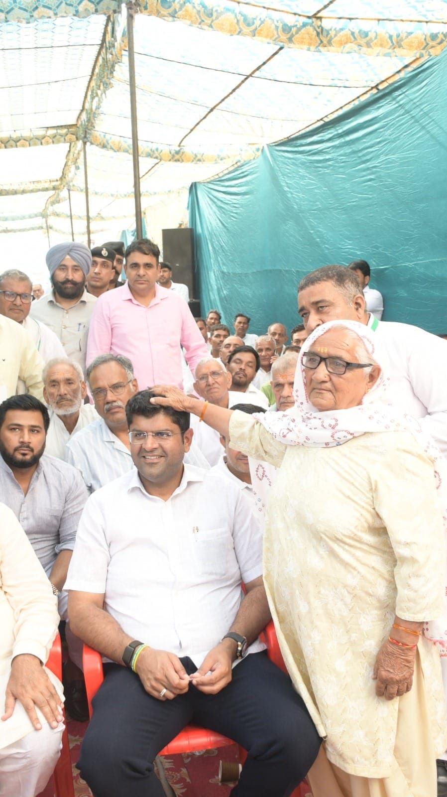 एक बुज़ुर्ग महिला आशीर्वाद देते हुए दुष्यंत चौटाला के सिर पर हाथ रखे हुए