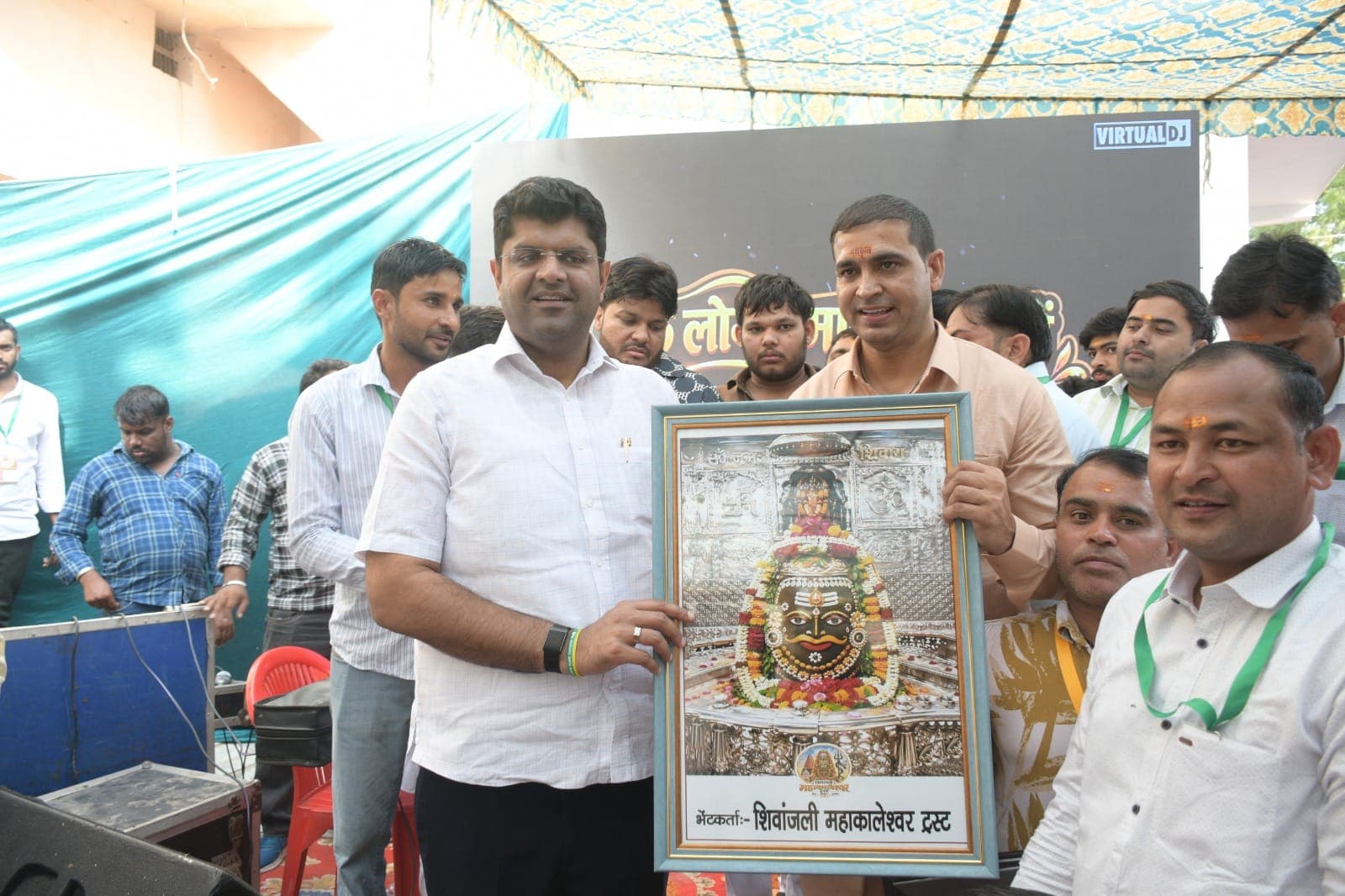 महाकालेश्वर का फ्रेम किया चित्र थामे दुष्यंत चौटाला और रविंदर सांगवान, आसपास स्वयंसेवक