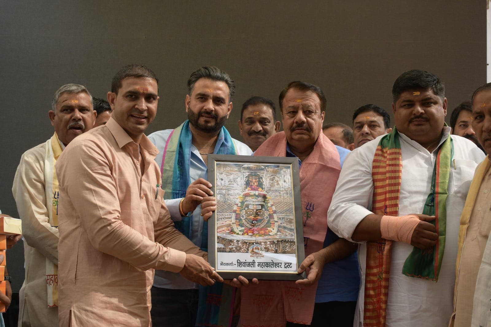 मंच पर अतिथियों की कतार को फ्रेम किया चित्र भेंट करते रविंदर सांगवान